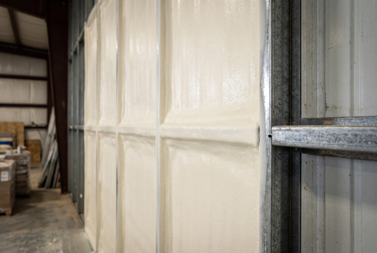 Dense closed-cell spray foam applied to metal wall panels and steel framing